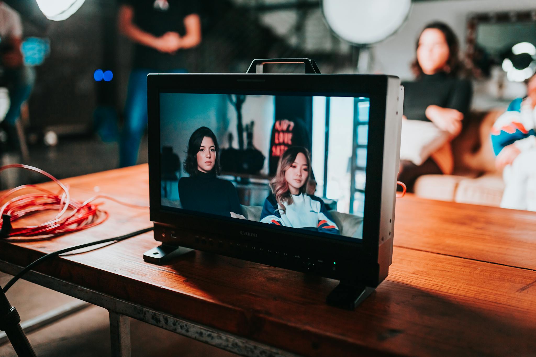 A professional photoshoot setup displaying two women on a monitor in a studio environment.